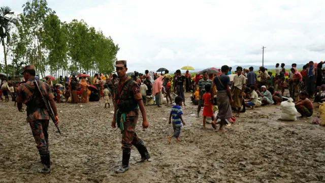 Members of the Border Guard Bangladesh (BGB) are seen on duty as they detain hundreds of Rohingya refugees in an open area after they crossed the border, in Teknaf, Bangladesh