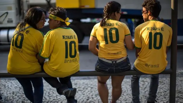 Pessoas com camisaapostas online em jogos de futebolque se lê 'deus é 10'