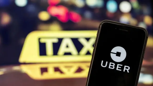 Celular com logo da Uber na tela e luminosomelhor horário para jogar cassino onlinetáxi ao fundo