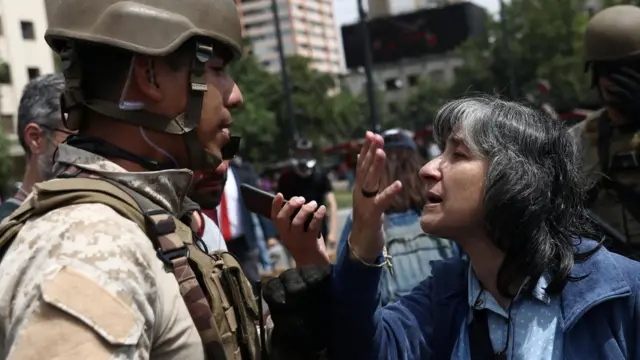 A demonstrator reacts in front of a soldier during a protest against the increase in subway ticket prices in Santiago