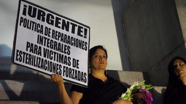 Una mujer sostiene un cartel durante una protesta exigiendo compensación en 2017