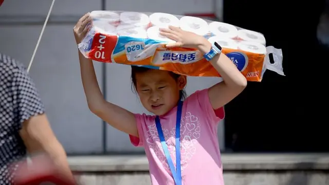 niña cargando un paquete de papel higiénico.