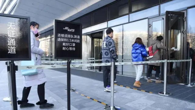 يصطف الناس أمام مداخل الشركات في بكين حتى تقاس درجات حرارتهم ويجري التحقق من هويتهم