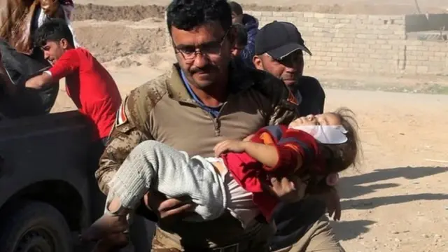 मोसुल के तहरीर ज़िले में एक घायल बच्ची को ले जाते इराक़ी सैनिक.