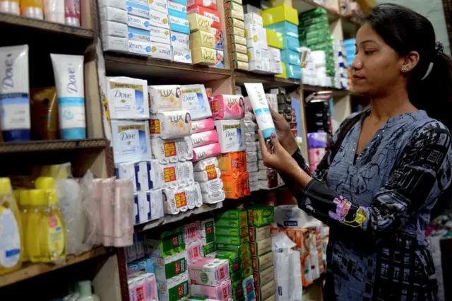 Mujer escoge una crema en una tienda.