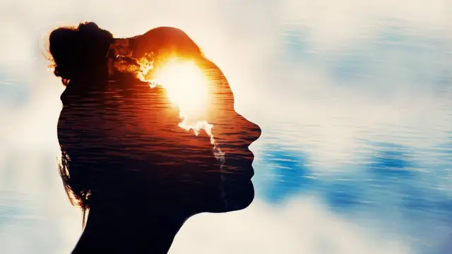 Una mujer en sombra y dentro de su cabeza aparecen rayos de luz