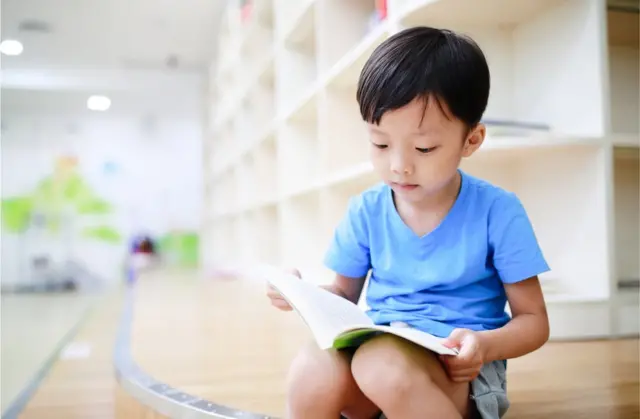 Un niño chino leyendo en una biblioteca.