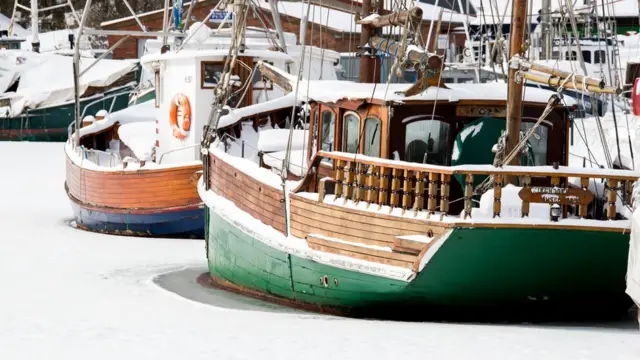 Snow-covered boats moored at the port of Kirchdorf on the Baltic Sea island of Poel, north-eastern Germany, where bays froze due to permafrost and night temperatures below -10C, on February 27, 2018