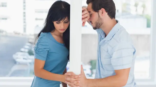 Pareja separándose en una ventana