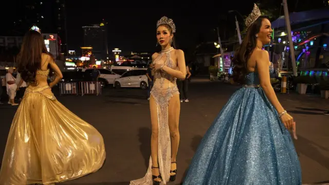 Thai cabaret dances wait for tourists for photos which brings in added revenue for them after a performance outside the Alcazar theater in Pattaya