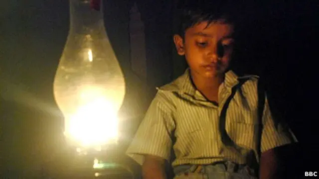 बल्ब की रोशनी में बैठा बच्चा