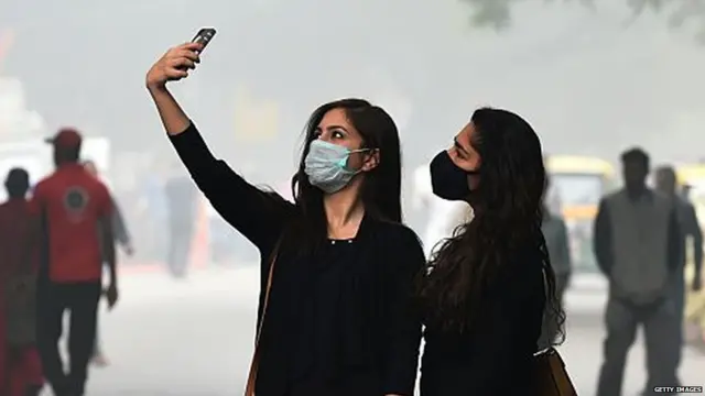 મેડિકલ માસ્ક પહેરીને પ્રદૂષણથી બચવાનો પ્રયાસ કરી રહેલી બે યુવતીઓની તસવીર