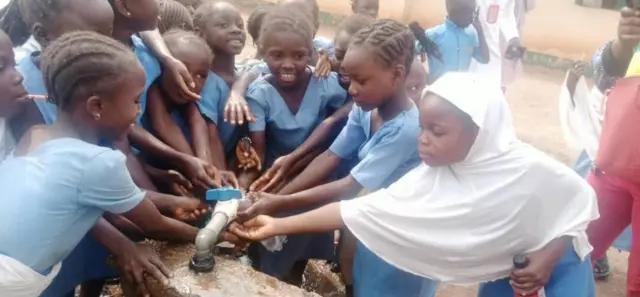 Children dey play wit di running water for dia school