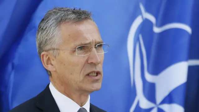 NATO Secretary General Stoltenberg pictured in front of a Nato flag