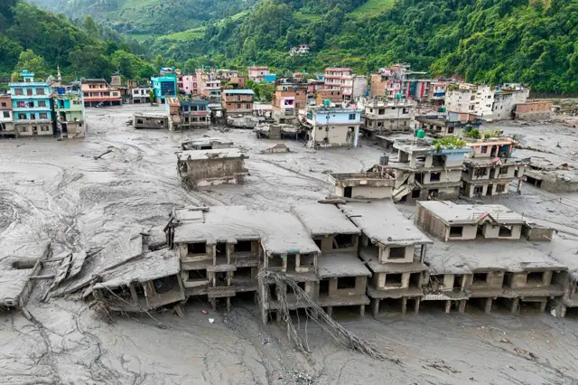 Casas cubiertas de lodo al lado de un río y casas coloridas que no sufrieron los efectos de la avalancha. 
