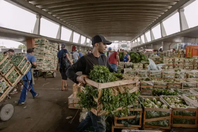 Homem carregando caixote com hortaliçasonabet de quem égrande armazémonabet de quem éalimentos