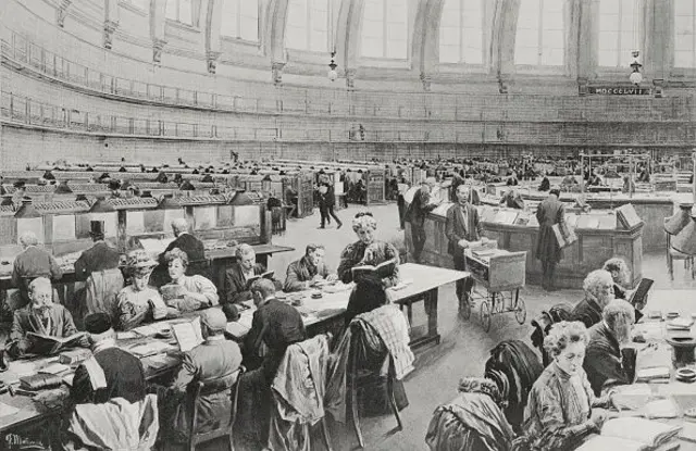 Büyük dairesel bir salında uzun masalarda kadınlar ve erkekler ellerinde kitaplarla okuma yapıyorlar, siyah beyaz. Merkezdeki dairesel masa danışma işlevi görüyor. 