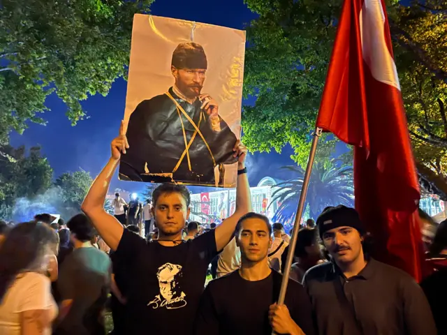 Mehmet, Ayberk ve Yusuf (Soldan sağa). Mehmet'in elinde Atatürk portresi, Ayberk'in elinde Türk bayrağı var.