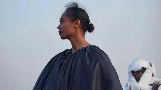 Black woman wey wear black cloth 