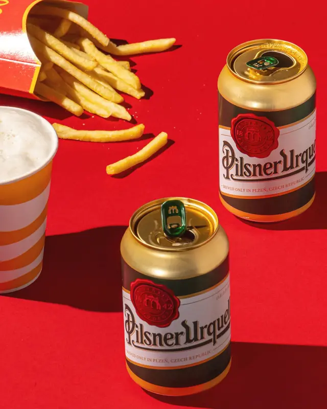 Банка з пивом та картопля фрі на червоному тлі