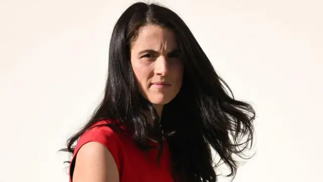 Un primer plano de Tatiana Schlossberg con el cabello largo y un top rojo