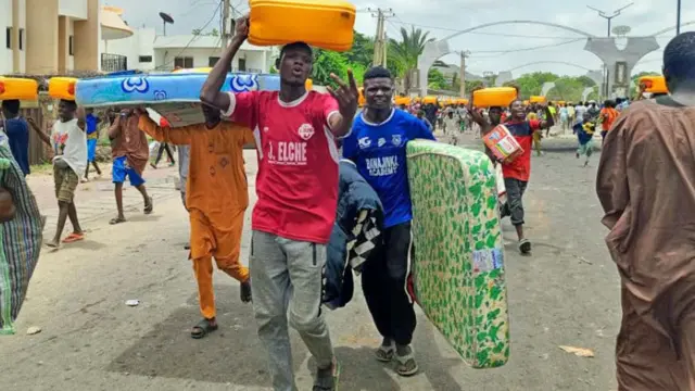 Des personnes emportent des cartons remplis d'huile de cuisson végétale et des matelas à Kano, Nigeria - 1er août 2024