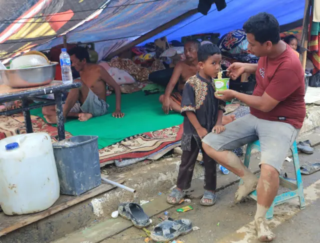 Warga korban banjir menyuapi anaknya saat berada di tenda pengungsian sementara di atas jembatan Kota Kuala Simpang, Kabupaten Aceh Tamiang, Aceh, Rabu (3/12/2025).