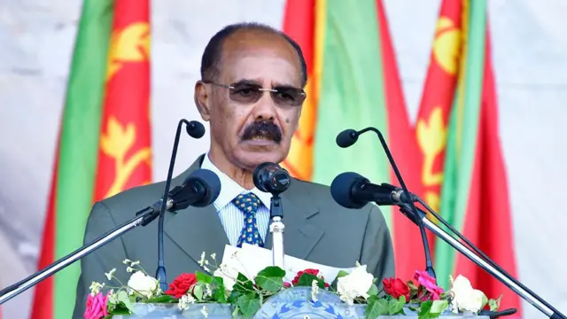 ፕሬዝዳንት ኢሳያስ አፈወርቂ ድምጽ ማጉያዎች የተደረደሩት አንትሮስ ፊት ቆመው ንግግር ሲያደርጉ