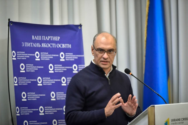 Чоловік в окулярах біля мікрофона