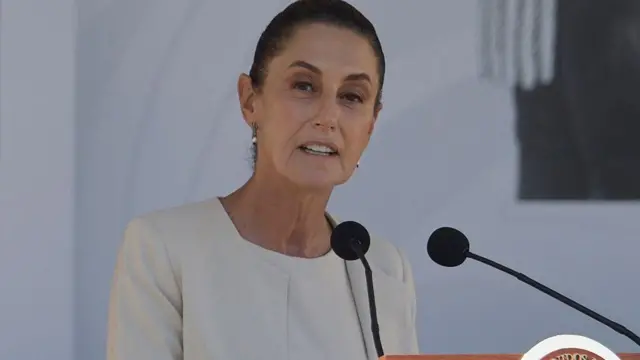  Claudia Sheinbaum con un vestido blanco en una rueda de prensa.