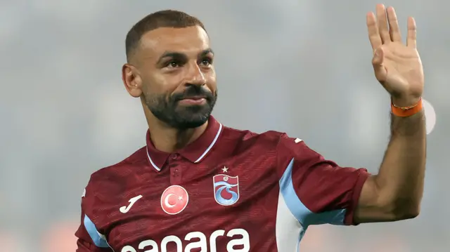 محمد صلاح يرفع يديه ويرتدي قميص نادي طرابزون التركي لكرة القدم