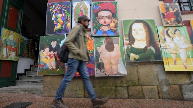 Um homem caminha ao lado de réplicas de desenhos do artista colombiano Fernando Botero em seu aniversário de 90 anos em Bogotá, em 19 de abril de 2022