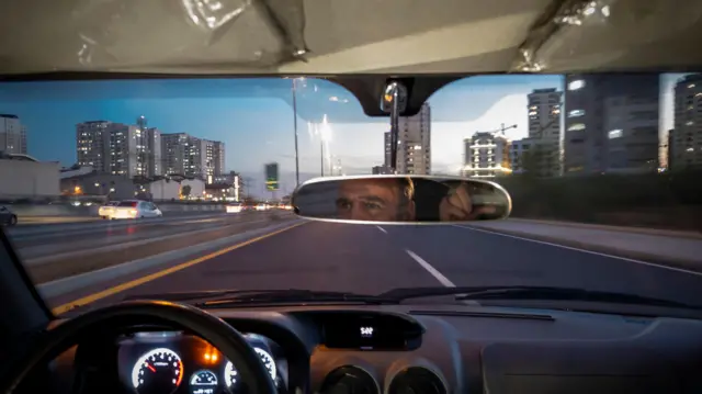 راننده یک تاکسی اینترنتی در محله چیتگر در شمال‌غرب تهران، در بزرگراه رانندگی می‌کند.