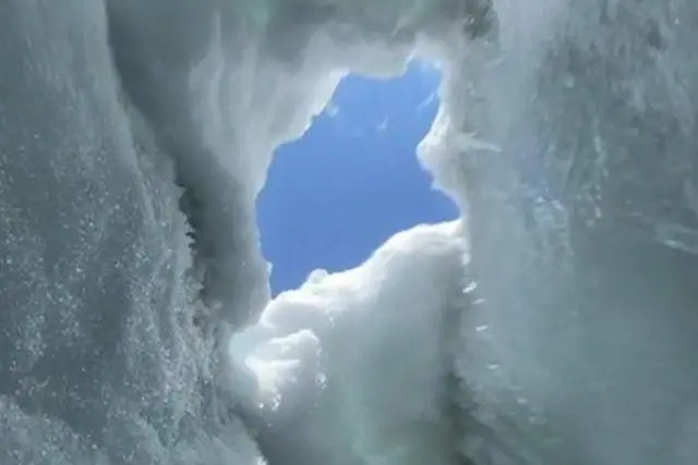 Un agujero de nieve con el cielo azul al fondo.