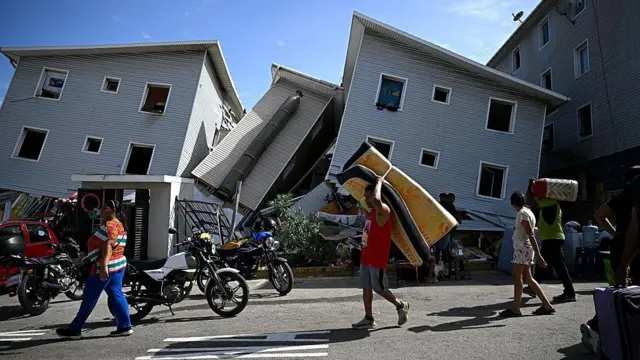 Un hombre transporta un colchón junto a edificios residenciales dañados tras un terremoto en Catia La Mar, estado La Guaira, a unos 30 km al noroeste de Caracas, el 25 de junio de 2026.