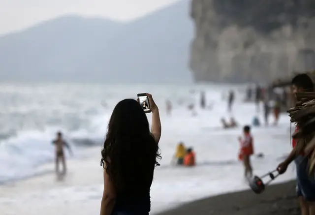 2017 yılından Lazkiye'nin bir plajının görüntüsü. Bir genç kadın selfie çekiyor.