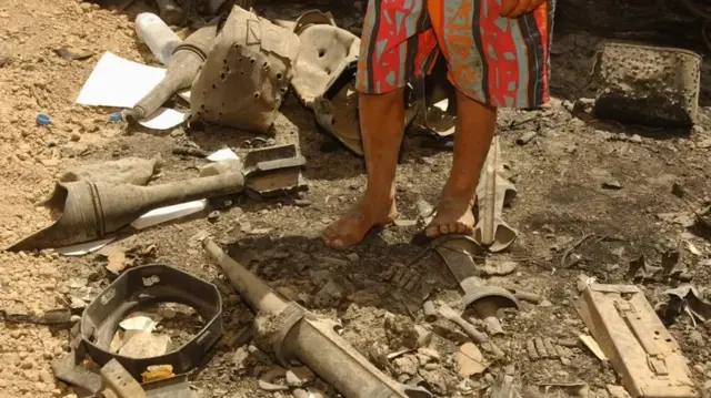 Un homme, pieds nus, sur des débris d'un obus à l'uranium appauvri.