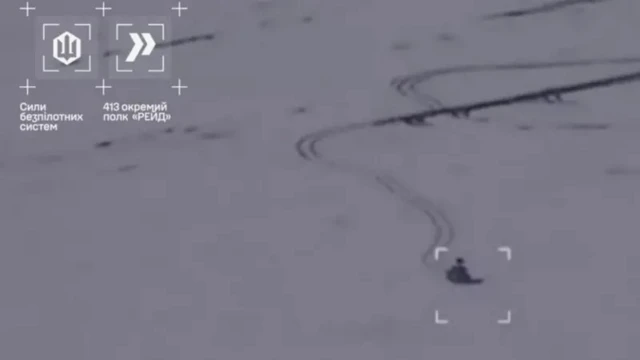 Кадр съемки с дрона, атака на движущуюся внизу по снегу единицу военной техники