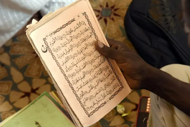 Un homme lisant le Coran dans une mosquée.