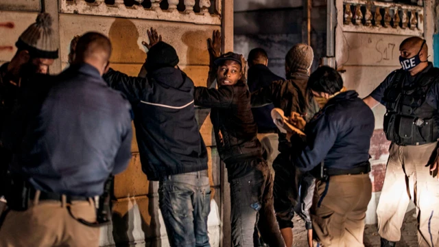 
Des policiers de la ville du Cap, en Afrique du Sud, ordonnent à des hommes de mettre leurs mains contre un mur pour être fouillés et interrogés - juin 2020.