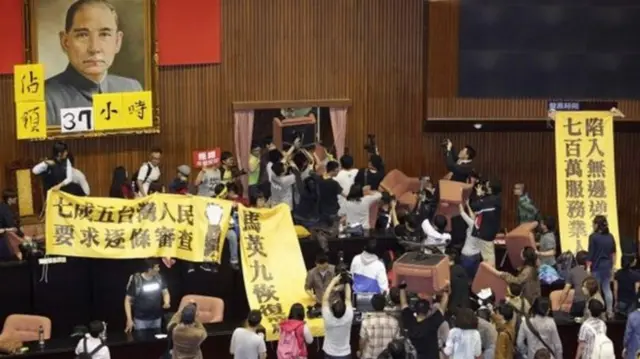 입법원을 점거한 청년 시위대가 현수막과 의자를 들고 항의하는 모습