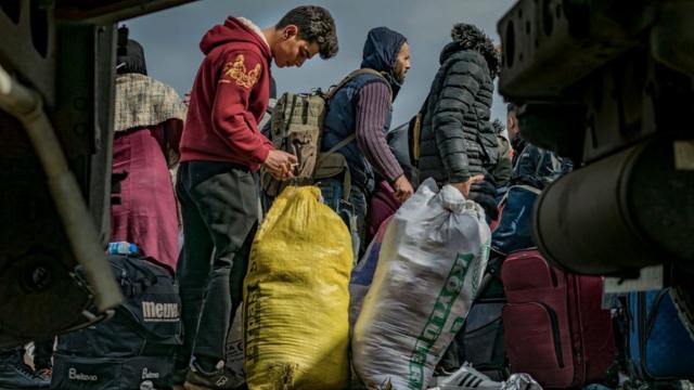 Refugiados sírios esperam em uma fila no posto de fronteira turco de Cilvegozu.  Muitos sírios estão voltando para suas casas depois que o violento terremoto na Turquia tornou suas condições mais difíceis