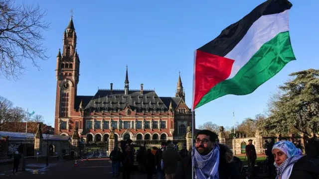 Un homme tient un drapeau palestinien devant la Cour internationale de justice à La Haye, Pays-Bas, le 26 janvier 2024.