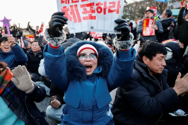 People in South Korea celebrate after parliament passes a motion to impeach President Yoon Suk Yeol