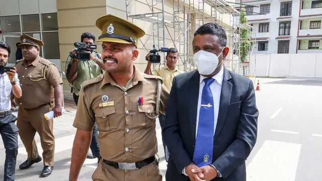 2025 සැප්තැම්බර් 23 වන දින ආගමන හා විගමන පාලක ජනරාල් හර්ෂ ඉලුක්පිටිය රැගෙන යන බන්ධනාගාර නිලධාරියෙක් 