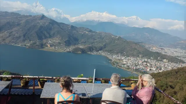 ဟိမဝန္တာက အမ်နာပူနာတောင်ကြောကို ထိုင်ခုံကနေထိုင်ပြီးကြည့်နေတဲ့ ခရီးသွားတွေရဲ့ ကျောဘက် ပုံစံကို ရိုက်ကူးထားခြင်း