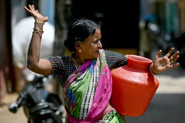 नगर निगम के नल से पानी भरकर ले जाती हुई महिला