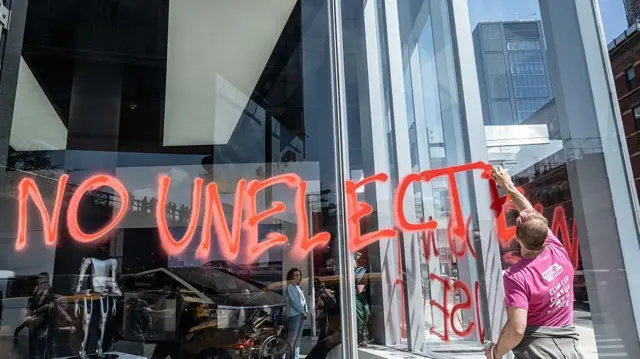 İklim aktivisti Extinction Rebellion üyeleri, 22 Nisan 2025'te New York'taki bir Tesla galerisinin camlarına DOGE karşıtı mesajlar yazıyor.