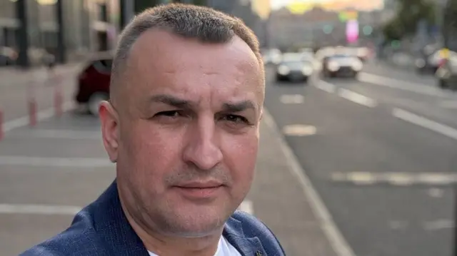 Чоловік в синьому піджаку на фоні дороги та міста 