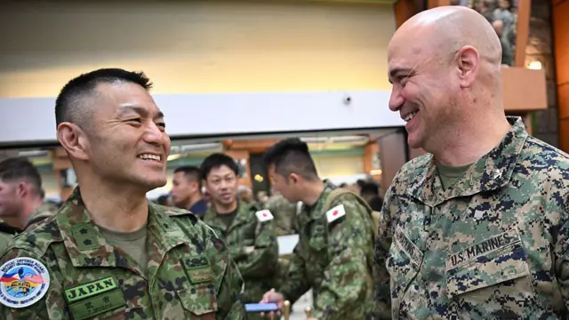 Генерал-майор Тосикату Муся (слева) из Сил самообороны Японии беседует с офицером морской пехоты США во время церемонии открытия ежегодных совместных военных учений «Баликатан» («Плечо к плечу») в лагере Агинальдо в городе Кесон, пригороде Манилы, 20 апреля 2026 года.